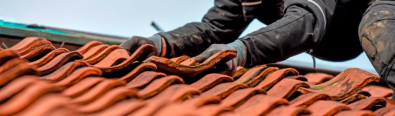 Dachdecker mit Sicherheitsausrüstung arbeitet auf einem Hausdach im Rahmen einer Dachsanierung in Wiesbaden.