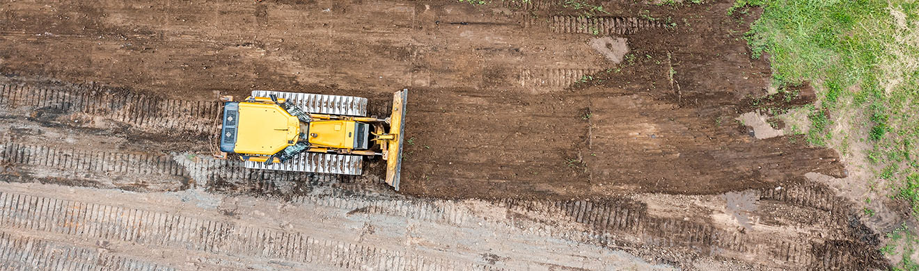 Ein gelber Bagger begradigt bei Erdarbeiten in Wiesbaden ein Feld