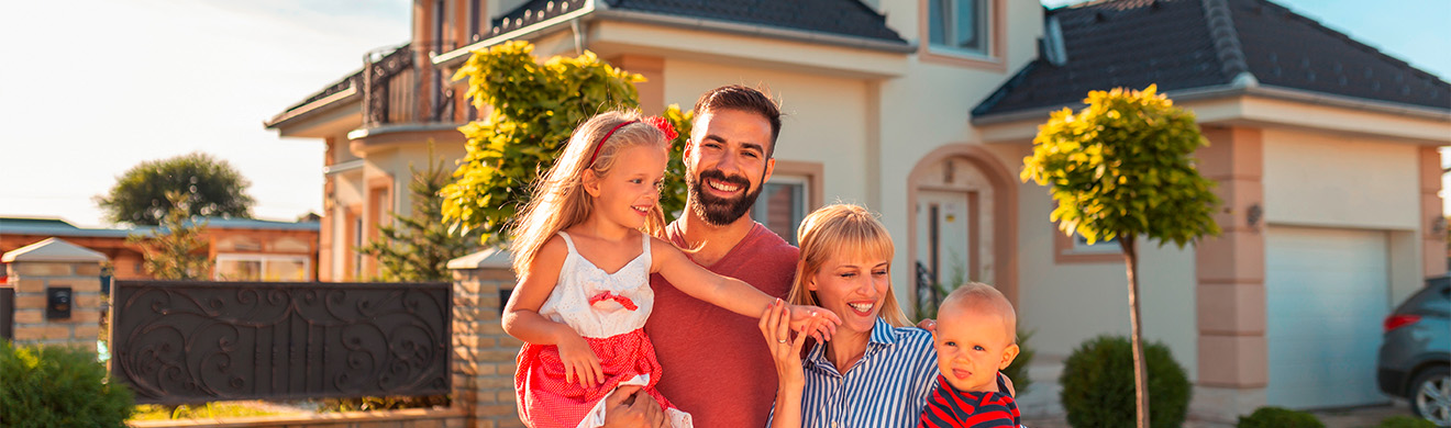 Glückliche Familie steht vor ihrem neuen Haus in Wiesbaden und feiert den Einzug in ihr Eigenheim.