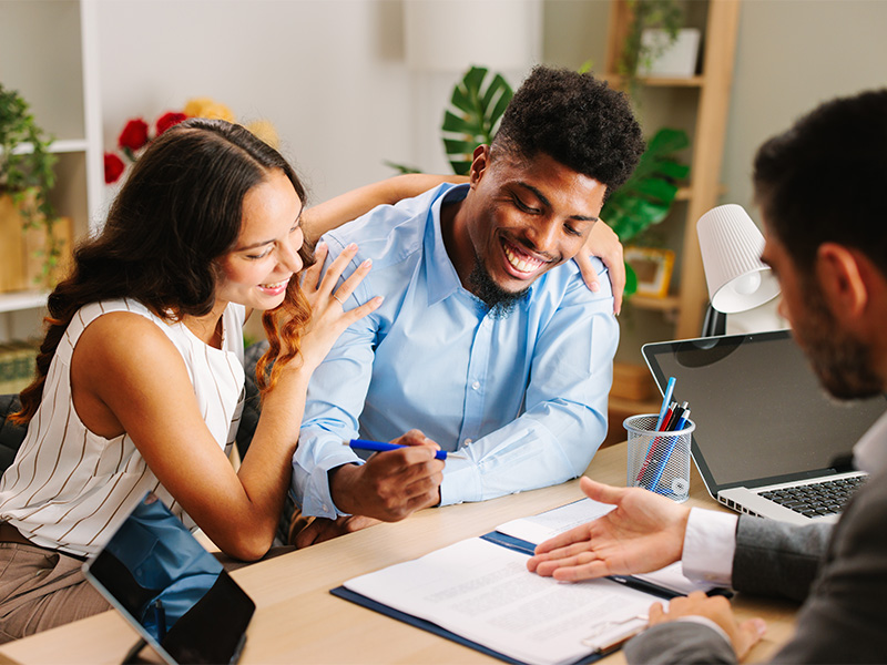 Junges lateinamerikanisches Paar unterschreibt einen Immobilienvertrag mit einem Makler in einem Büro in Wiesbaden.
