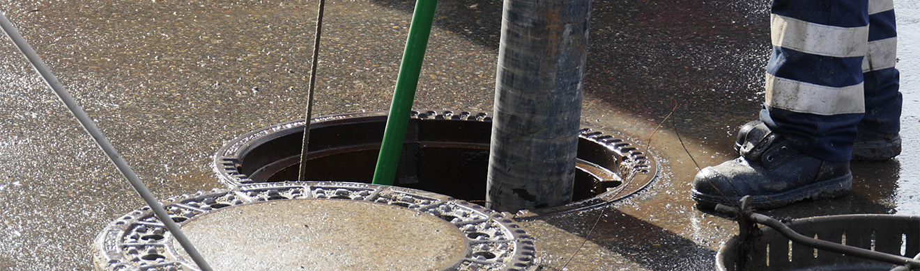 Techniker in Arbeitskleidung reinigt Kanalrohr in Wiesbaden professionell zur Vorbeugung von Verstopfungen und Abwasserschäden.