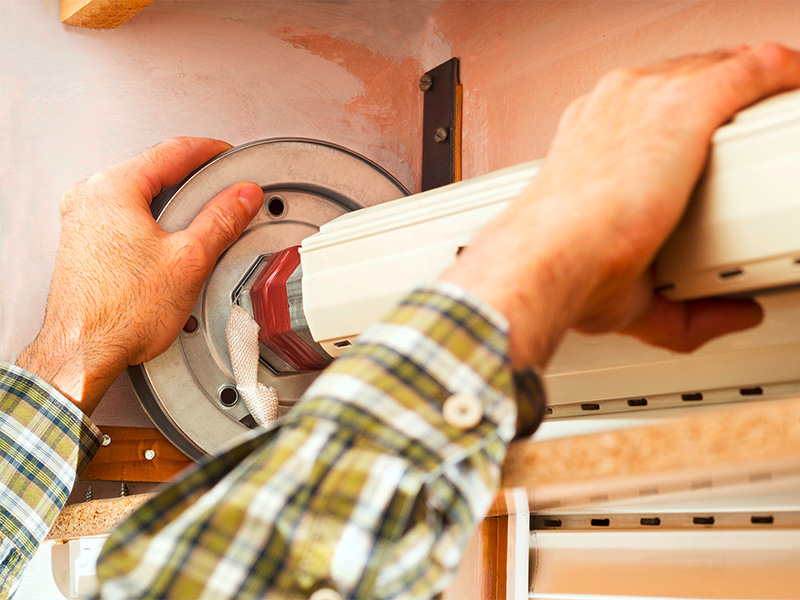 Handwerker repariert einen Rollladen am Fenster und überprüft die Mechanik für eine zuverlässige Funktion.
