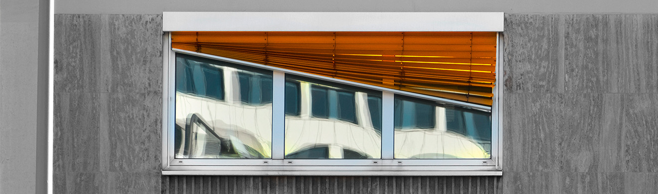 Defekte Jalousie an Hausfassade mit Fenster, beschädigte Lamellen beeinträchtigen den Sonnenschutz und die Funktionalität.
