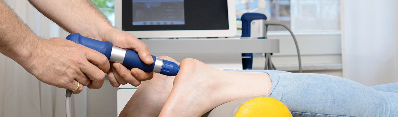 Anwendung von Stoßwellentherapie in Wiesbaden an der Ferse einer liegenden Person durch medizinisches Fachpersonal.